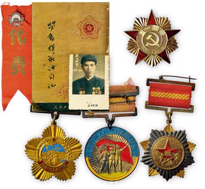 五十年代徽章等一組共7件，詳分：1954年“全國人民慰問人民解放軍代表團贈”紀念章1枚；“全世界人民一致團結起來”紀念章1枚；“五一紀念”章1枚；1954年中國人民共和國交通部贈“華南公路修建紀念章”1枚；“送舊迎新1949-1960”軍人照片1張；1950年人民出版社出版《勞動模范訪問記》1本，內中夾有“國慶紀念”章和“代表”紅色布條；保存甚佳，敬請預覽