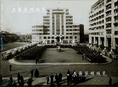 1937年淞滬會戰期間“上海法租界防衛軍閱兵儀式”歷史老照片一張，尺寸380×278mm，如此大幅者極為難得；照片上的地點位于上海愛多亞路公共租界中央巡捕房大廈門前，旁邊的建筑乃是杜月笙氏開設的“中匯銀行大樓”，照片上的部隊是法國第十六殖民地步兵團（RIC）第二連和一個輕型坦克連；此乃老上海歷史之珍貴影像，源于法國回流，挖掘自昔年該防衛軍軍官家族之遺存，保存極佳，敬請預覽