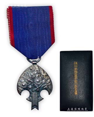 康德二年（1935年）“滿洲帝國皇帝訪日紀念章”1枚，附帶原盒；此章乃1935年4月溥儀首次訪日時所發行，委托日本著名的雕刻家日名子實三設計，大阪造幣局制作，銀質鰩形，正面雕鑄一束象征偽滿洲國的蘭花和象征日本國的菊花的花卉圖案，花束彩帶上面鑄有“一德一心”四字；日本回流之上佳品相，敬請預覽
